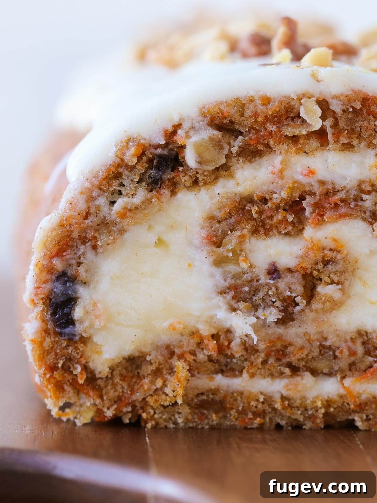 Spiced Carrot Cake Swirl 2 A perfectly sliced carrot cake roll, showing the layers of moist cake and creamy white cream cheese frosting, garnished with chopped walnuts.