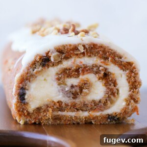 Spiced Carrot Cake Swirl 6 carrot cake roll with cream cheese buttercream on wooden board.