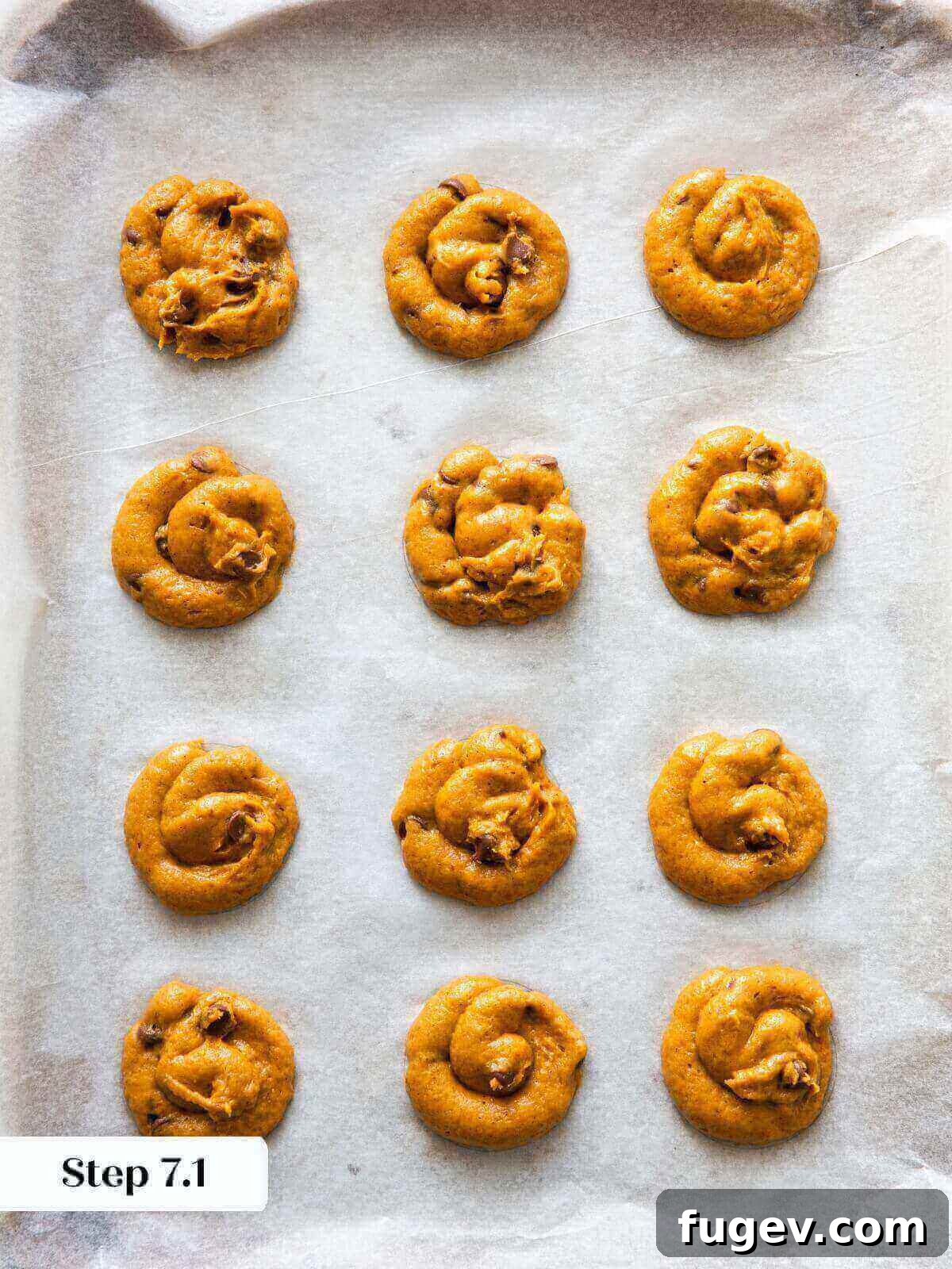 Spiced Pumpkin Chocolate Delights 10 Rows of unbaked pumpkin chocolate chip cookie dough balls neatly arranged on a parchment-lined baking sheet.