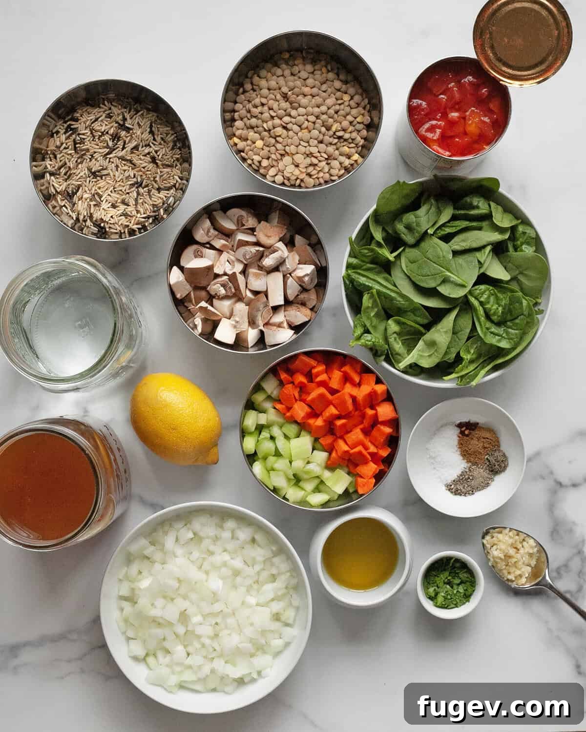 Hearty Lentil Wild Rice Soup 3 Various fresh ingredients laid out, including lentils, wild rice, onions, carrots, celery, mushrooms, seasonings, broth, spinach, and lemon.