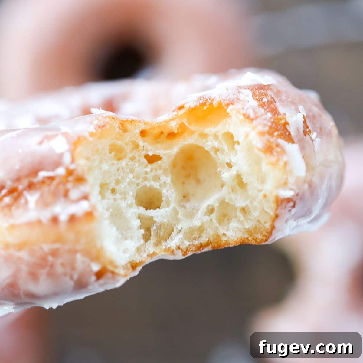 Homemade Krispy Kreme Style Donuts 3 A Krispy Kreme style donut with a bite taken out, showcasing its soft, airy interior and thin, sweet glaze.