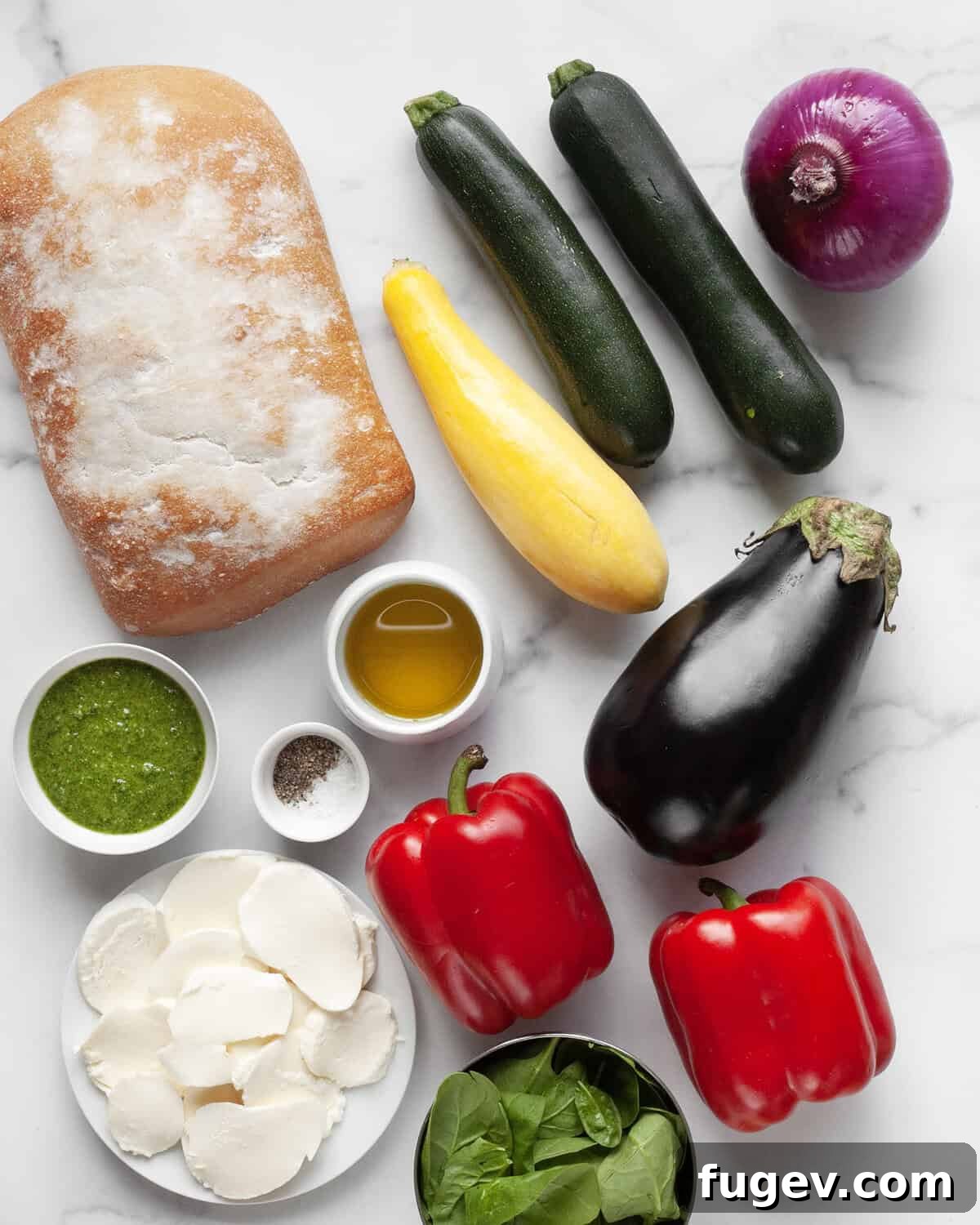 Mediterranean Grilled Vegetable Ciabatta 3 A selection of fresh ingredients including ciabatta bread, colorful vegetables, basil pesto, olive oil, salt, pepper, and fresh mozzarella cheese.