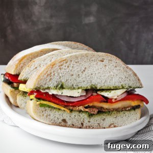 Mediterranean Grilled Vegetable Ciabatta 8 A perfectly assembled grilled vegetable ciabatta sandwich, cut in half, showcasing layers of colorful vegetables, pesto, and mozzarella.