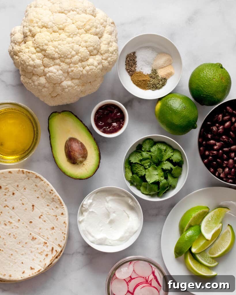 Smoky Chipotle Cauliflower Tacos 3 A vibrant flat lay of ingredients for chipotle roasted cauliflower tacos, including fresh cauliflower, black beans, various spices, bright limes, creamy avocado, aromatic cilantro, Greek yogurt, and soft tortillas.