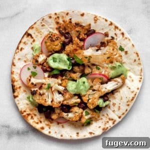 Assembled taco with cauliflower, beans and garnishes.