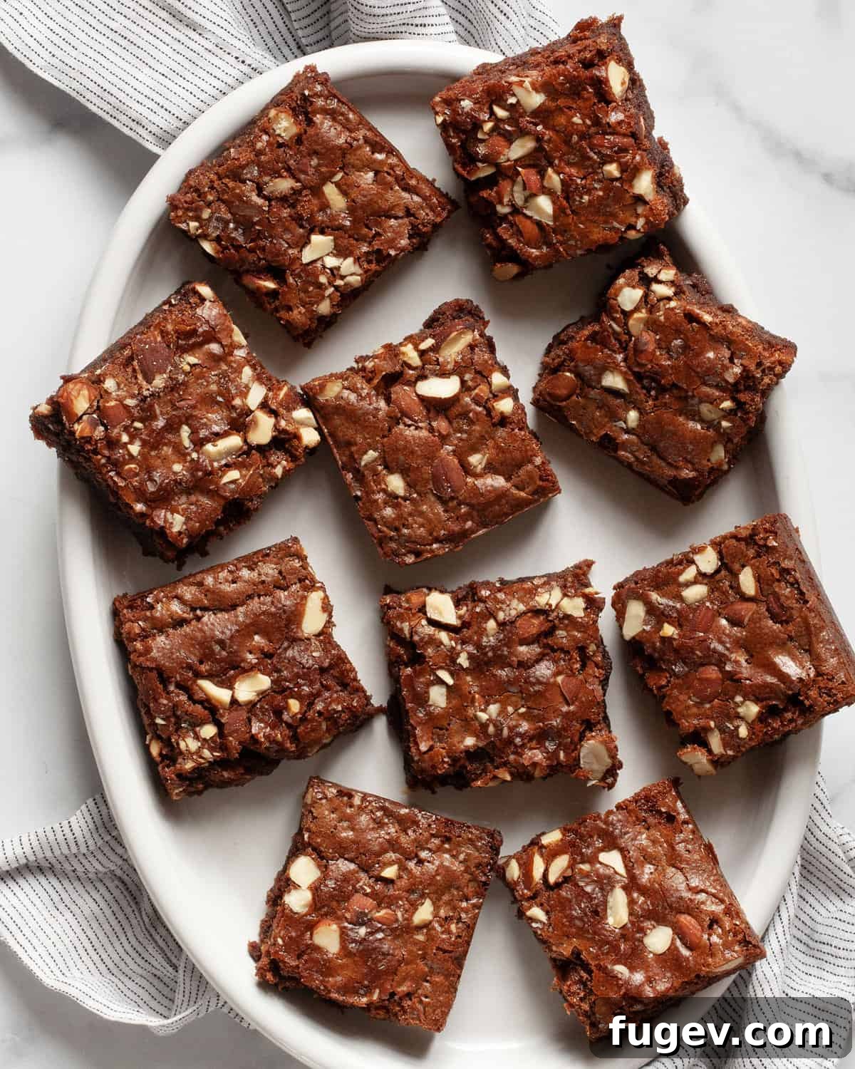 Milky Chocolate Almond Brownie Squares 7 A beautifully arranged stack of 10 fudgy milk chocolate almond brownies on an oval ceramic plate.