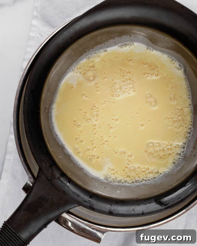 Pillowy Brioche Ice Cream Indulgences 7 Straining custard for ice cream into bowl