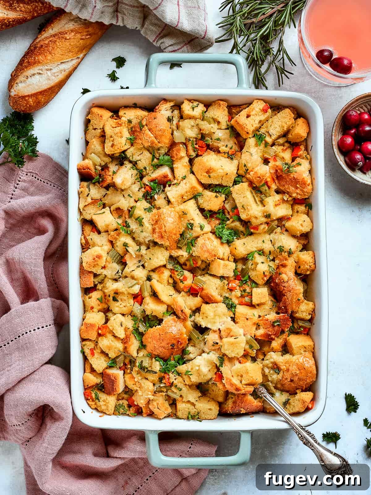Down-Home Southern Cornbread Dressing 17 Baked cornbread dressing beside a sliced baguette and fresh rosemary on a rustic table.