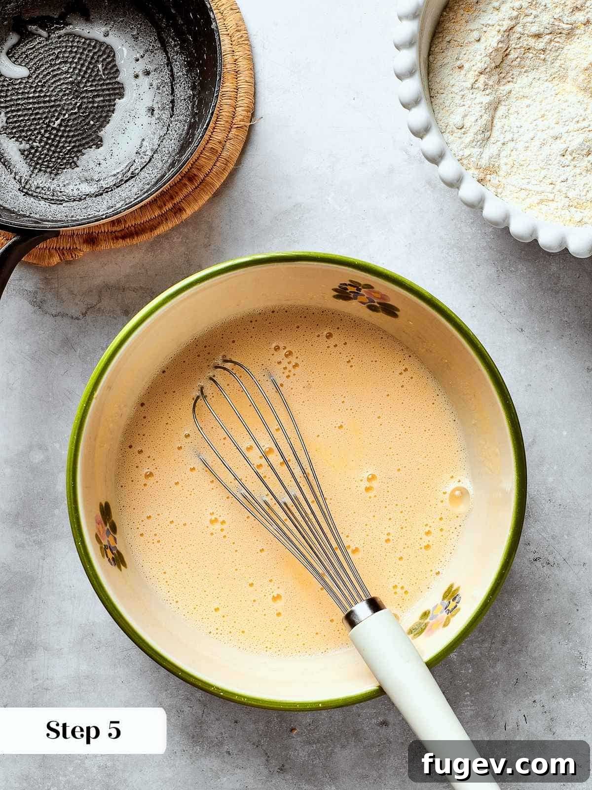 Down-Home Southern Cornbread Dressing 9 Milk being whisked into eggs in a bowl to create the wet ingredients for cornbread batter.