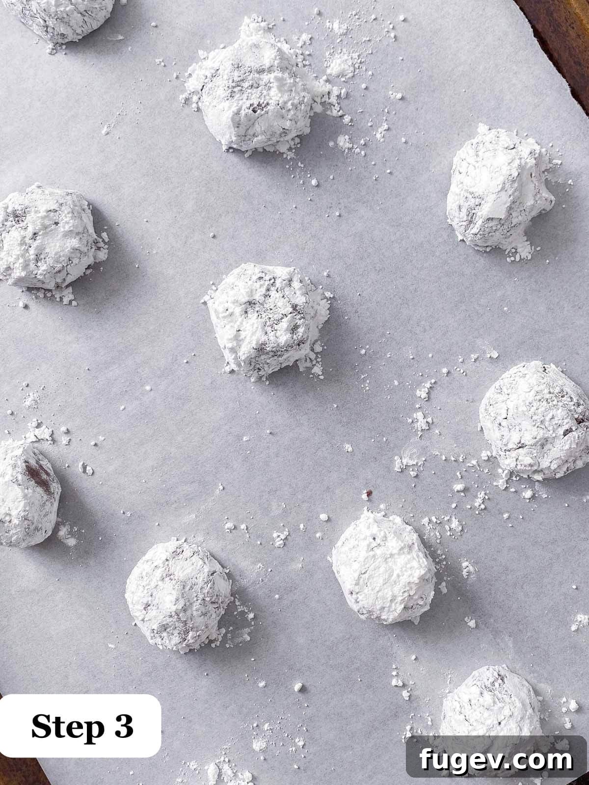 Fudgy Chocolate Crinkles 4 Close-up of chocolate crinkle cookie dough balls generously rolled in powdered sugar.