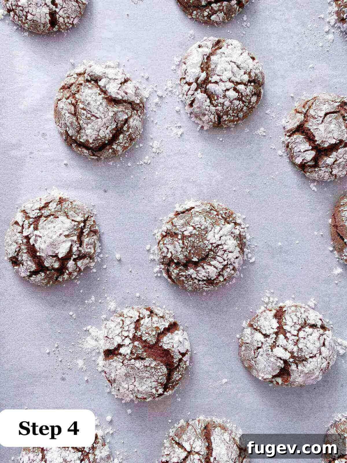 Fudgy Chocolate Crinkles 5 Freshly baked chocolate crinkle cookies on a baking sheet, showcasing their crackled tops.