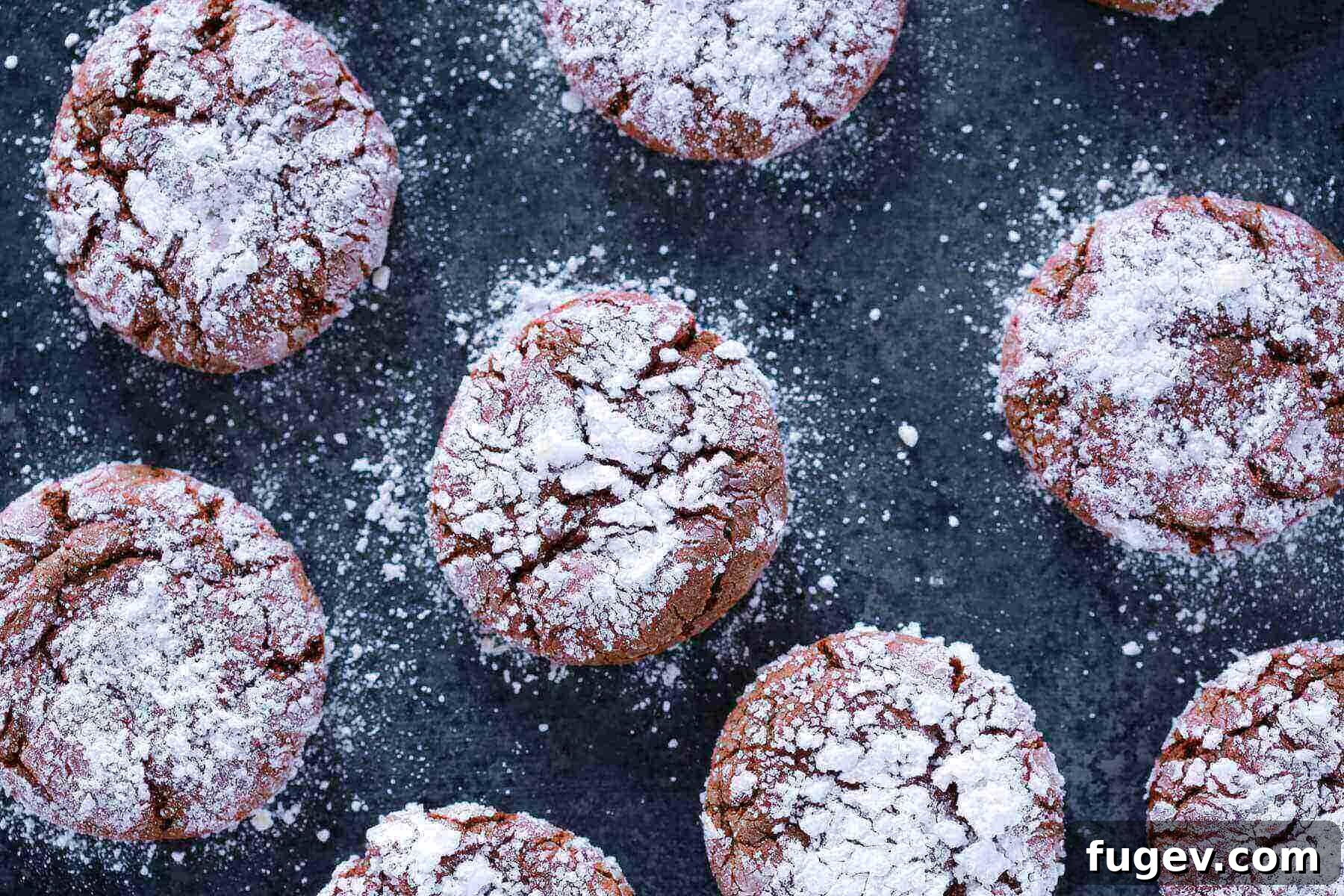 Fudgy Chocolate Crinkles 6 A batch of chocolate crinkle cookies cooling on a wire rack against a dark countertop.