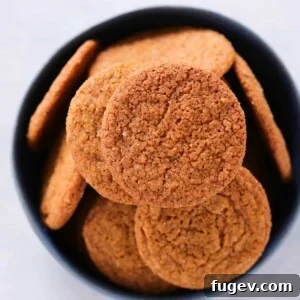 Old Fashioned Gingersnaps in a black bowl, garnished with cinnamon sticks.