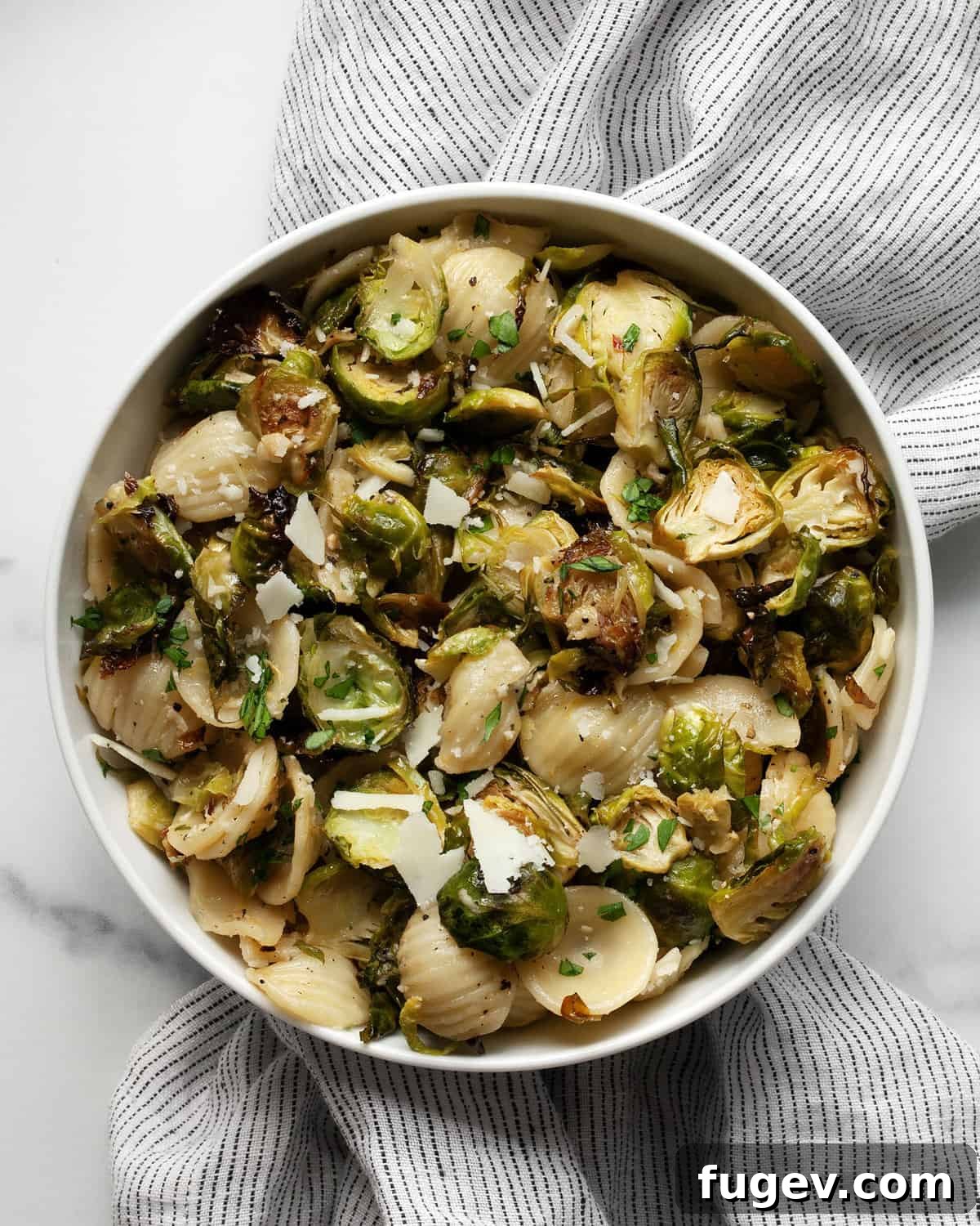 Caramelized Brussels Sprout Pasta 7 A small, cozy bowl of roasted Brussels sprout orecchiette pasta, elegantly garnished with a sprig of fresh herbs, offering a comforting and delicious leftover meal idea.
