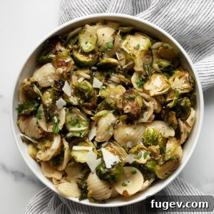 A beautifully presented bowl of roasted Brussels sprout pasta, garnished with fresh herbs and a sprinkle of cheese.