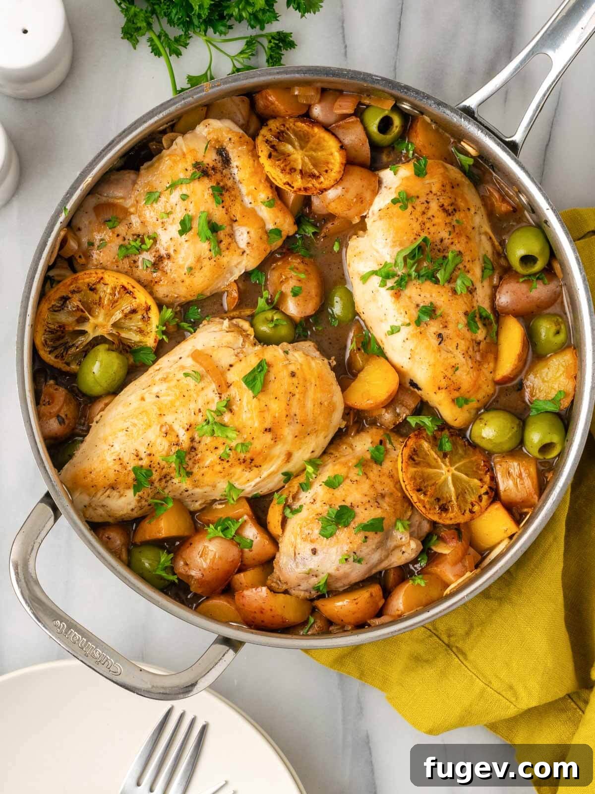 Zesty Lemon Chicken 2 Golden-brown lemon chicken, tender roasted potatoes, and vibrant fresh herbs beautifully arranged in an oven-safe pan, glistening with lemon-butter sauce.
