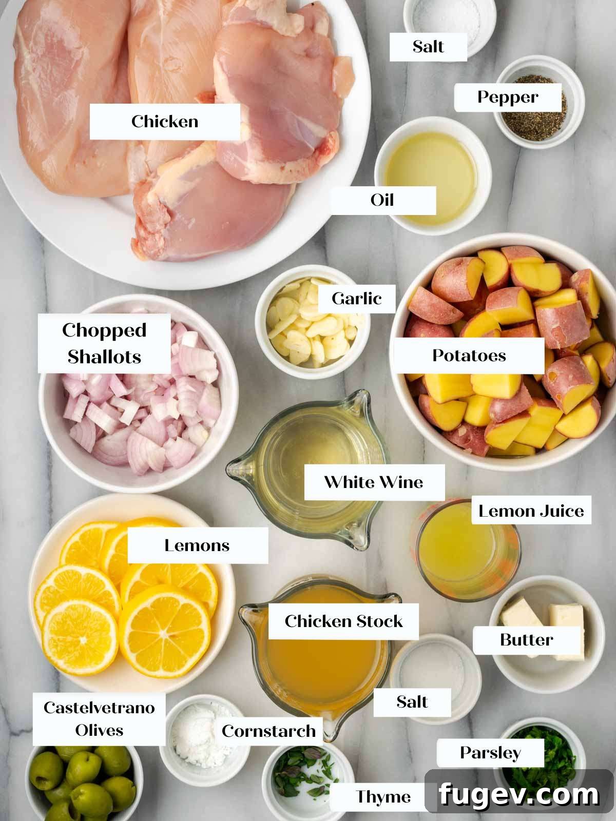 Zesty Lemon Chicken 4 Fresh ingredients for lemon chicken laid out beautifully on a marble surface, including whole lemons, raw chicken pieces, red potatoes, shallots, garlic, and fresh herbs.