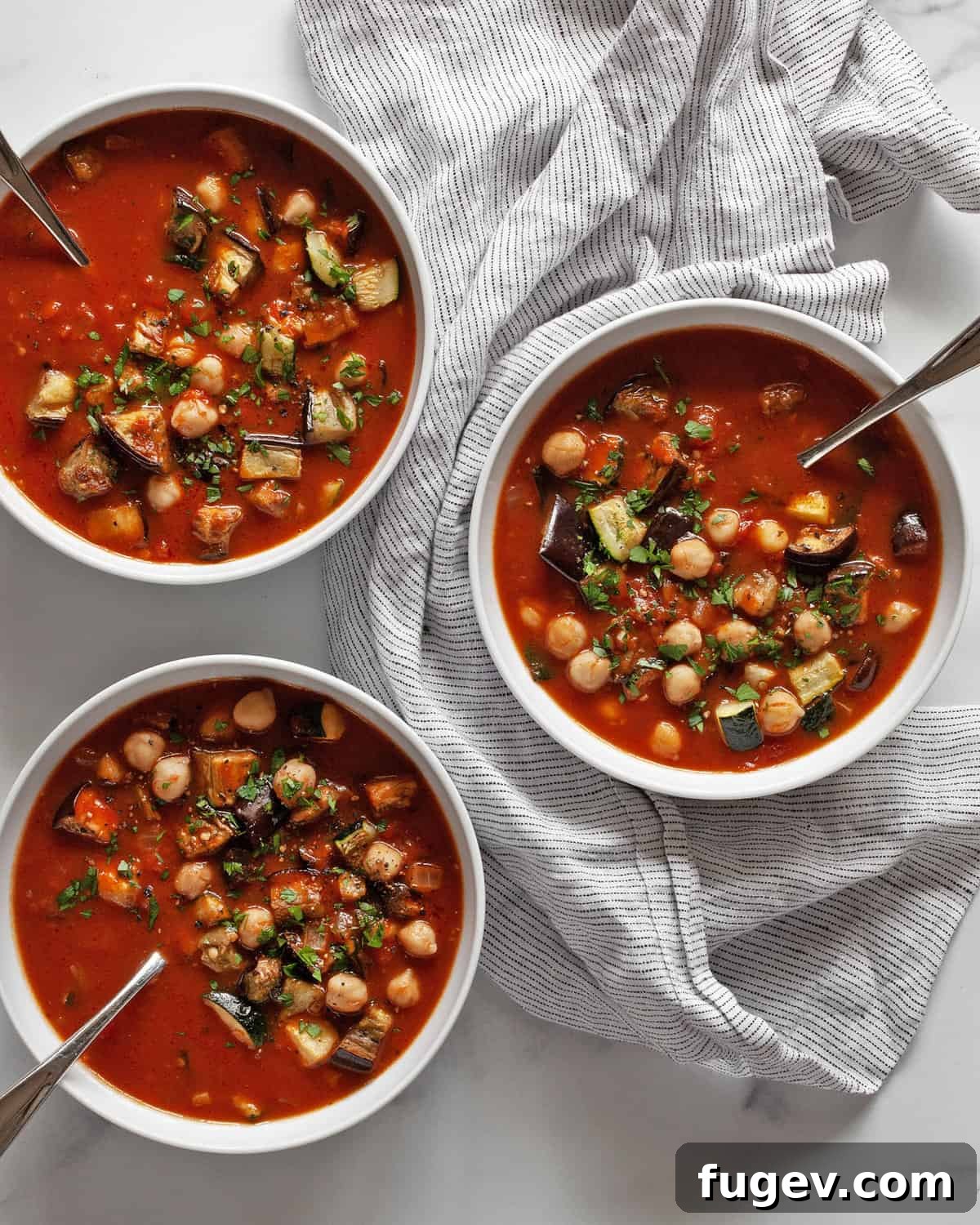 Mediterranean Eggplant and Chickpea Stew 2 Three beautifully arranged bowls of hearty roasted eggplant and zucchini stew, garnished with fresh herbs, ready to be served.