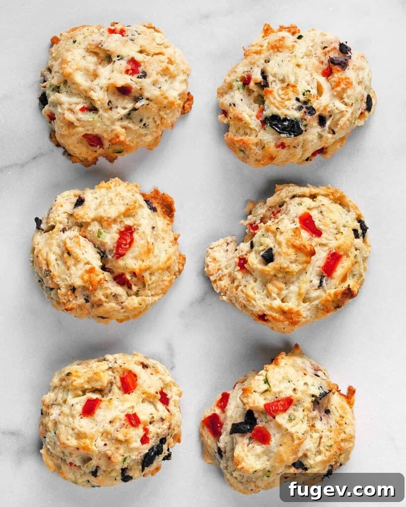 Crimson Chevre Scones 2 Golden-brown Red Pepper Olive Goat Cheese Biscuits cooling on a wire rack.