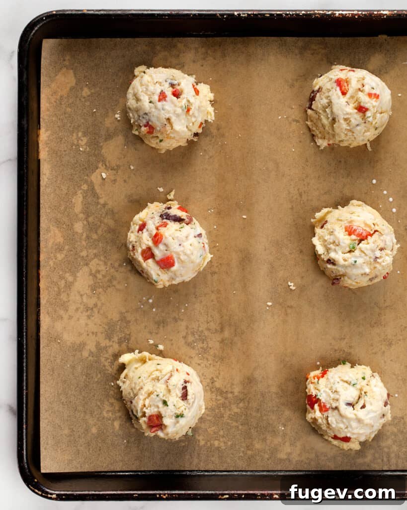 Crimson Chevre Scones 5 Dropping portions of biscuit dough onto a parchment-lined baking sheet.