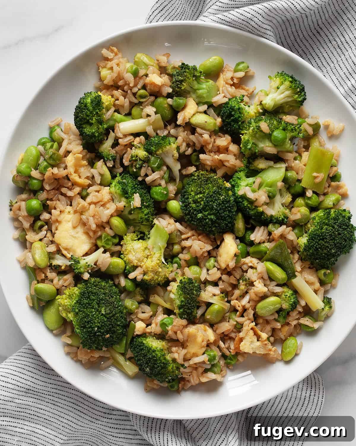 Nutrient-Packed Broccoli, Edamame, and Pea Fried Rice 2 Broccoli, pea and edamame fried rice on a plate, showcasing its vibrant green colors and fluffy texture.
