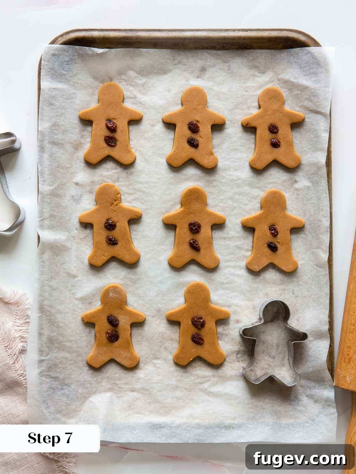 Melt-in-Your-Mouth Gingerbread Treats 8 Decorating gingerbread men with raisins before baking, on a parchment-lined baking sheet.