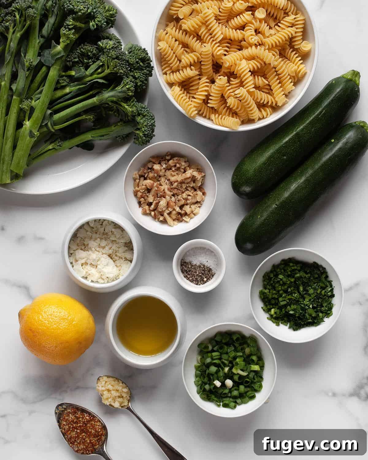 Rustic Roasted Broccolini Zucchini Pasta Salad 3 A flat lay photograph showcasing all the fresh, colorful ingredients required for the pasta salad, including broccolini, zucchini, pasta, lemon, walnuts, olive oil, feta, and fresh herbs.