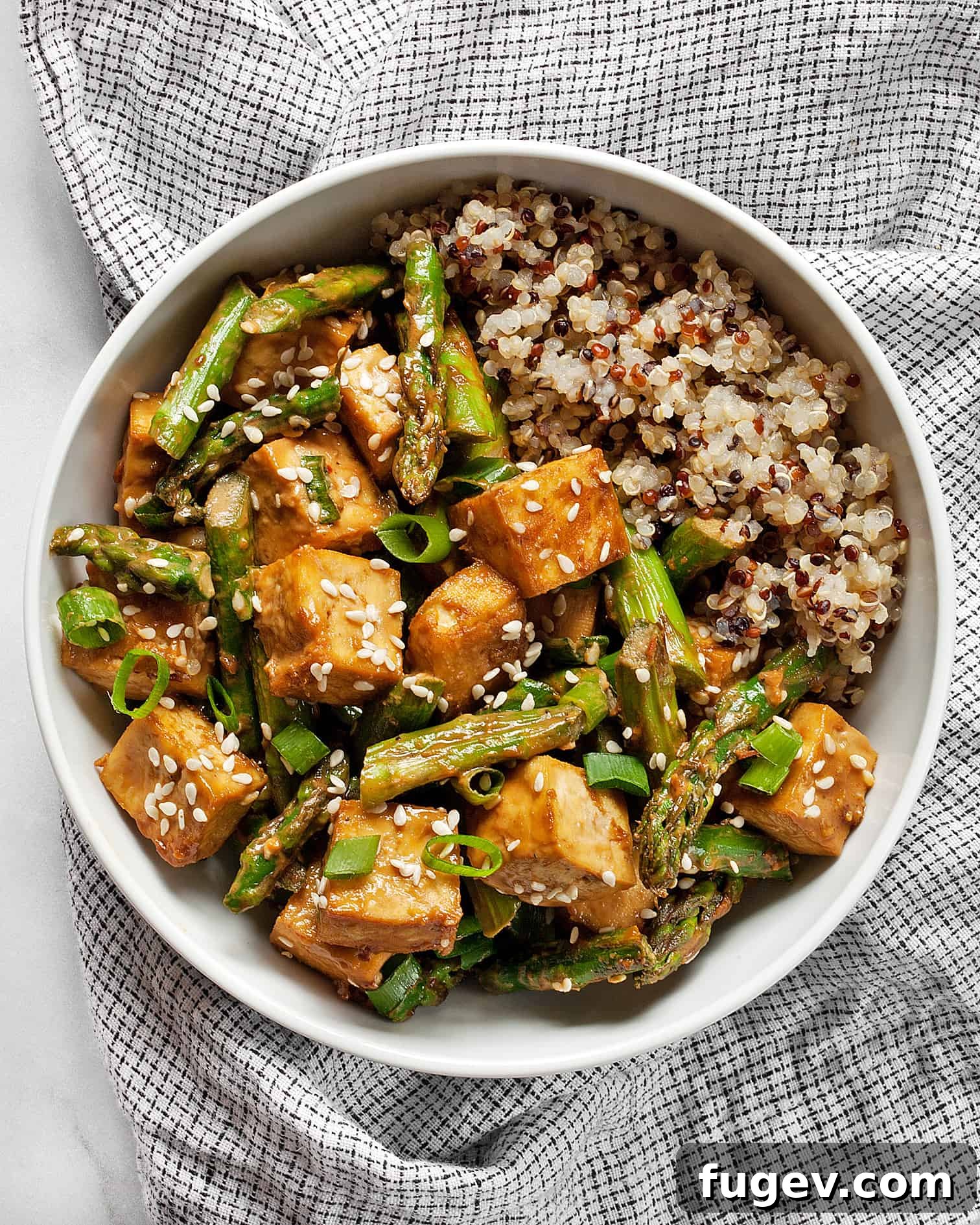 Crispy Sesame Tofu and Roasted Asparagus Sheet Pan Dinner 6 Close-up of a serving of sesame tofu and asparagus with a generous amount of sauce and garnished with scallions and sesame seeds.