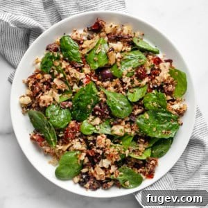 Crisp Roasted Cauliflower Grains 8 Roasted cauliflower rice with sun dried tomatoes, olives, artichokes and spinach on a plate.