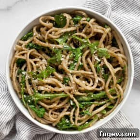 Arugula pesto pasta served in a small white bowl, garnished with fresh arugula leaves