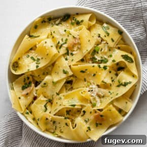 Elegant pappardelle pasta tossed with fresh green herbs in a small, stylish bowl