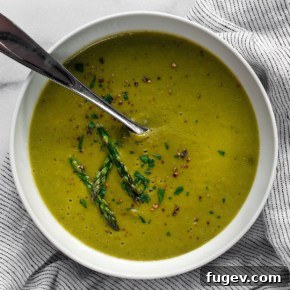 Creamy bowl of roasted asparagus soup, garnished with fresh herbs