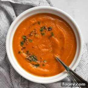 Rich roasted carrot soup, topped with fresh parsley and black pepper, in a comforting bowl