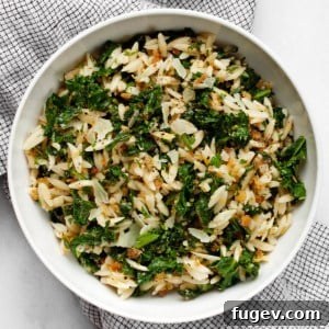 Lemon orzo in a bowl, garnished with fresh herbs and a lemon slice.