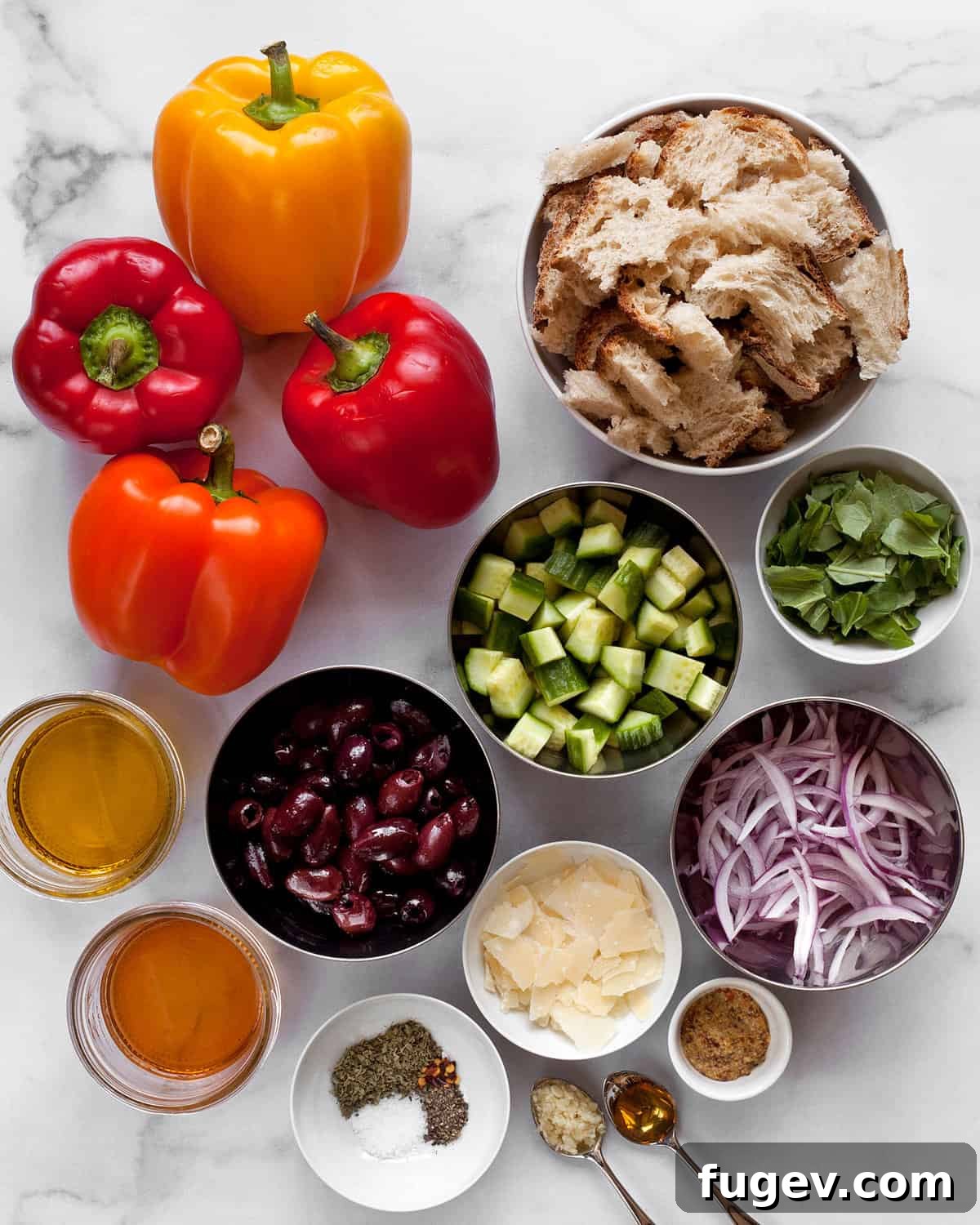 Fire-Kissed Pepper Salad 3 A colorful array of fresh ingredients for the roasted bell pepper salad, including whole bell peppers, cucumbers, olives, red onions, Parmesan, basil, bread, olive oil, and vinaigrette components.