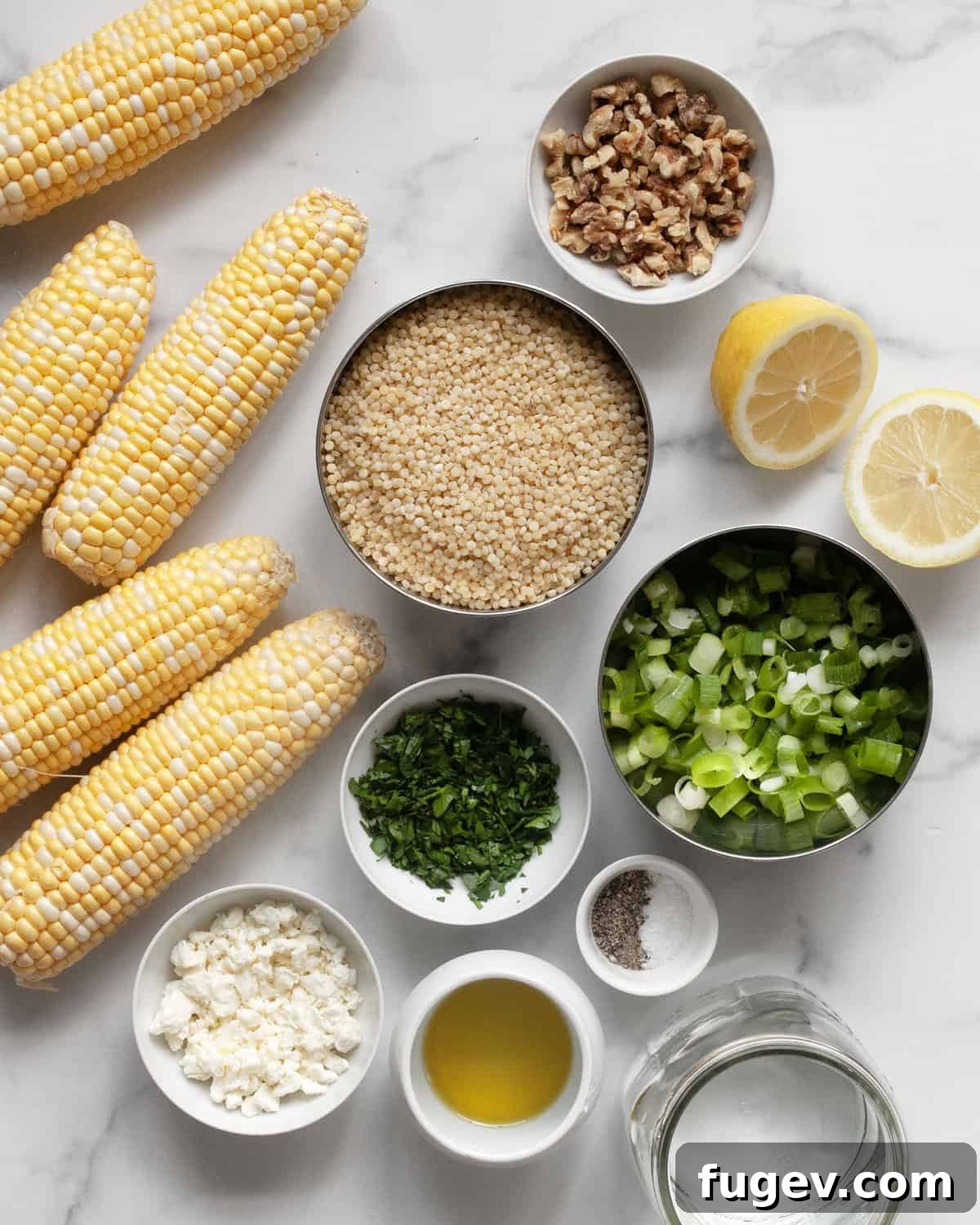 Smoky Corn Couscous Salad 3 A flat lay image displaying the fresh ingredients for grilled corn couscous: ears of corn, pearl couscous, a lemon, scallions, walnuts, feta cheese, and fresh parsley.