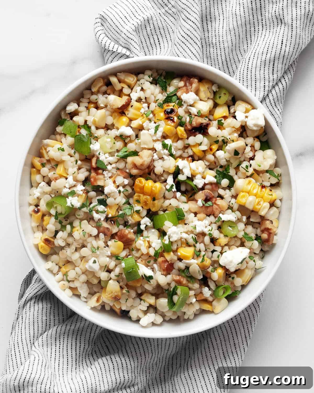 Smoky Corn Couscous Salad 7 A close-up of grilled corn pearl couscous artfully arranged in a rustic bowl, garnished with fresh herbs, ready to be served.
