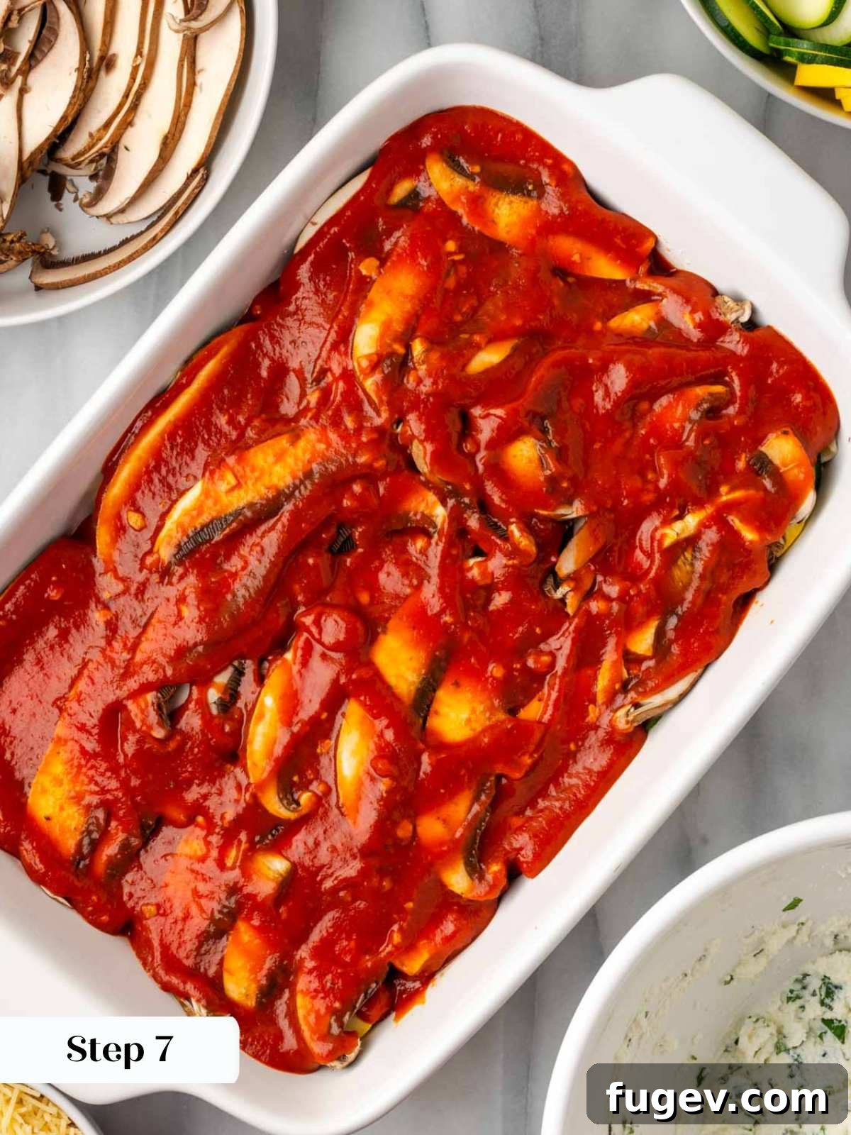 Vibrant Veggie Lasagna 11 Spreading a rich layer of tomato pasta sauce over the vegetable layers in a lasagna dish.