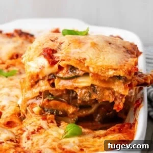 A mouth-watering slice of vegetable lasagna with cheese pulling, demonstrating its irresistible texture.