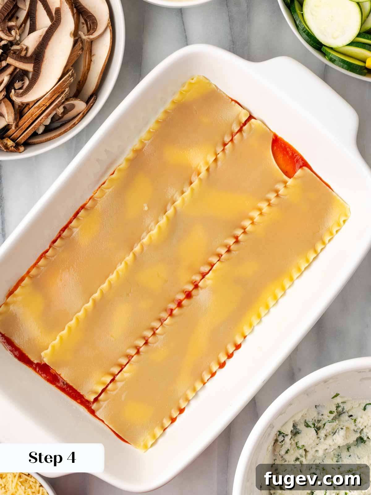 Vibrant Veggie Lasagna 6 Layering cooked lasagna noodles into a baking dish over a base of tomato sauce.