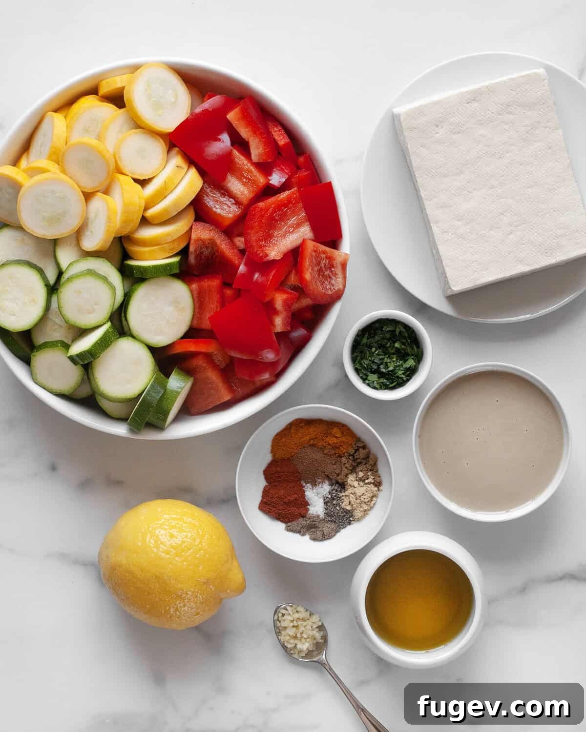 Spiced Grilled Tofu Shawarma 3 Ingredients for grilled tofu shawarma laid out: tofu, various spices, lemon, olive oil, tahini, fresh parsley, and garlic.