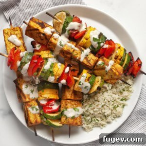 Grilled tofu and vegetable skewers with couscous on a plate.