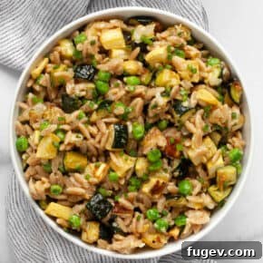 Creamy Parmesan orzo pasta with roasted squash, zucchini, and green peas in a serving bowl.