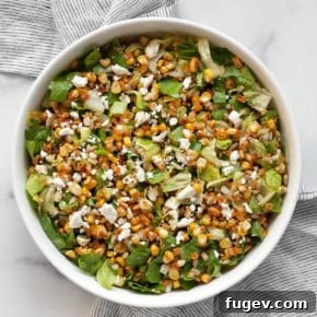 Chopped salad with roasted corn, romaine, feta and scallions in a bowl.