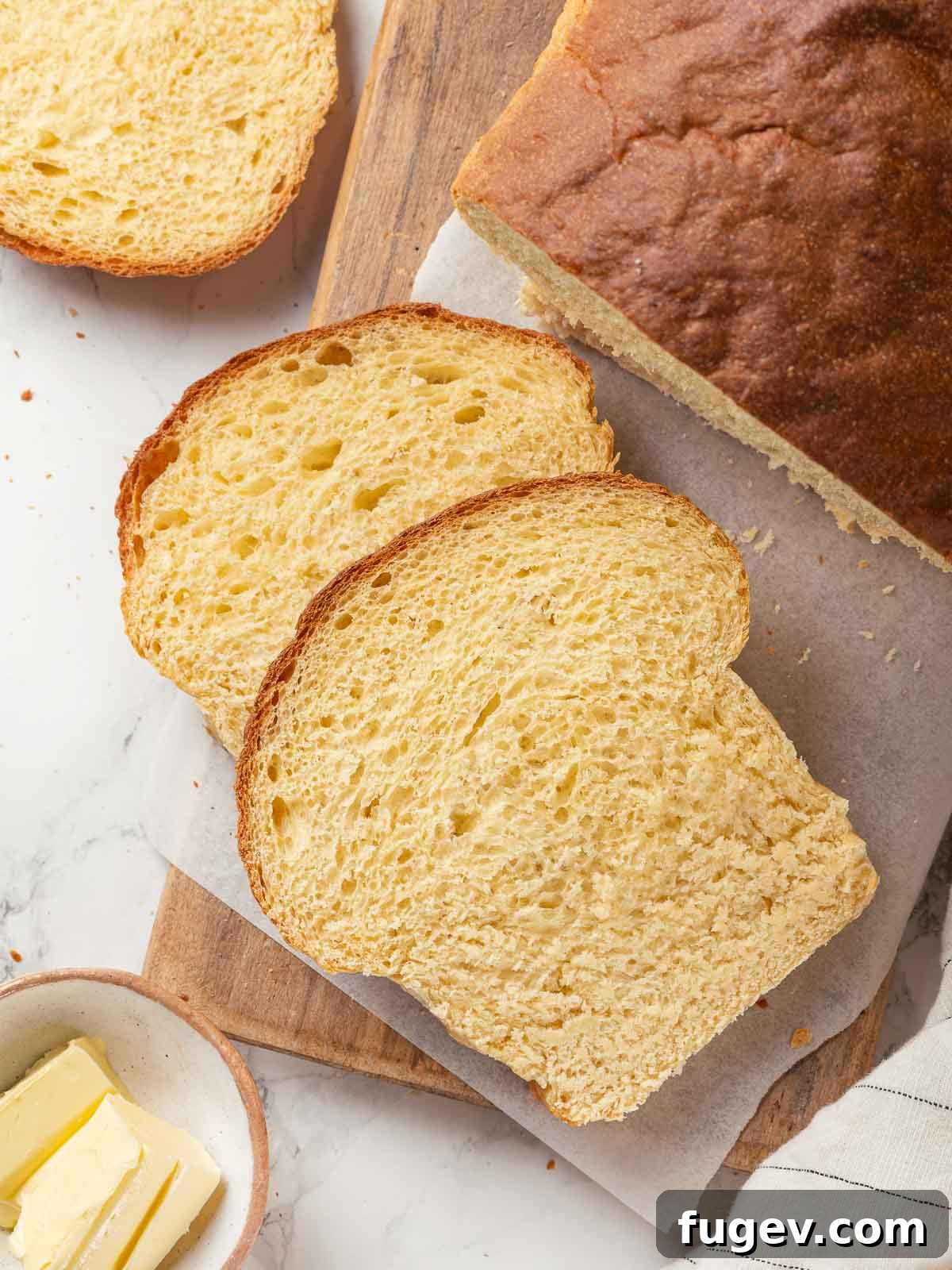 Pillowy Potato Loaf 23 A loaf of potato bread perfectly sliced on a rustic wooden cutting board.