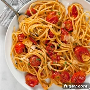 Spaghetti with burst cherry tomatoes on a plate.