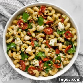 Pesto pasta salad with roasted tomatoes and mozzarella in a bowl.
