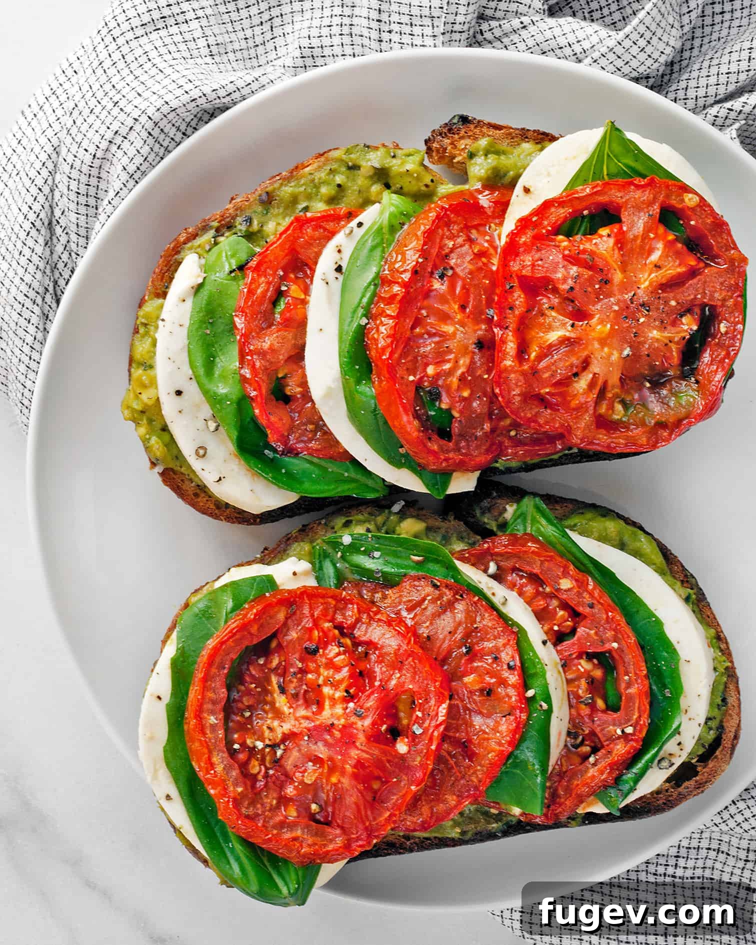 Fresh Caprese Avocado Toast 2 Delicious Caprese Avocado Toast, garnished with fresh basil leaves and roasted tomatoes.