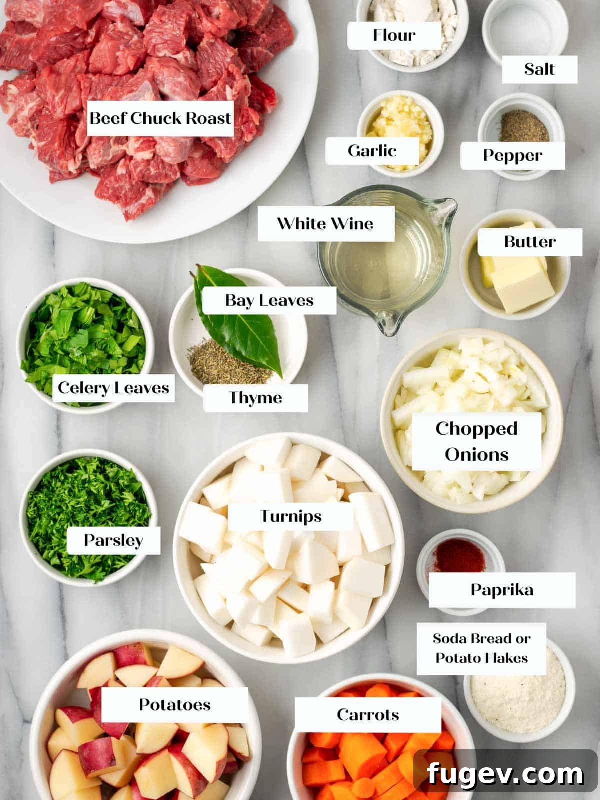 Classic Cast Iron Beef Stew 5 A selection of fresh ingredients for beef stew laid out on a marble countertop, including beef, vegetables, and herbs.