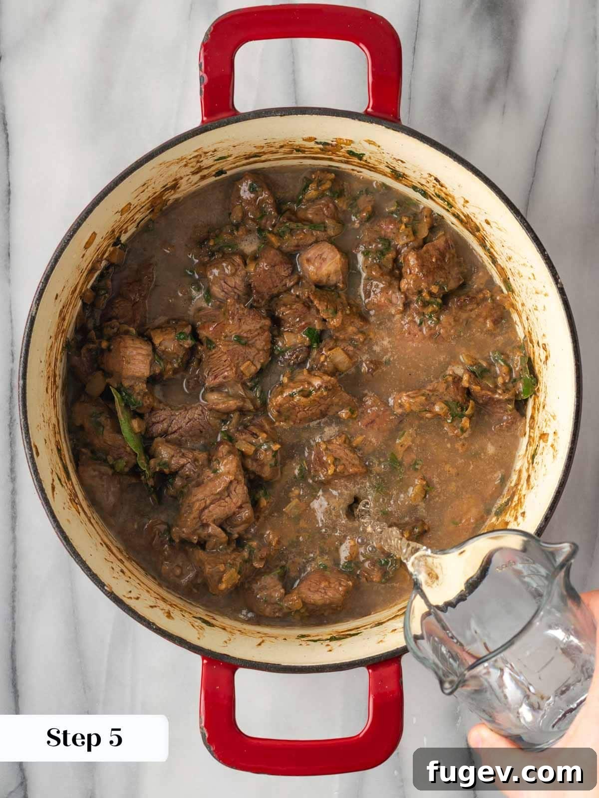 Classic Cast Iron Beef Stew 10 Adding water to beef stew in a Dutch oven, with meat and vegetables simmering.